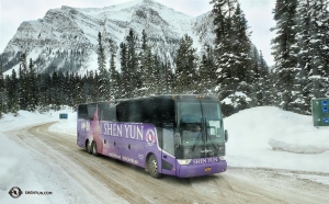 O vibrante ônibus da turnê do grupo do Shen Yun  acrescenta um toque de cor à neve branca e às pinheiros sempre-verdes.
